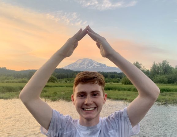 Intern making a triangle with hands and Mt. Adams in the background
